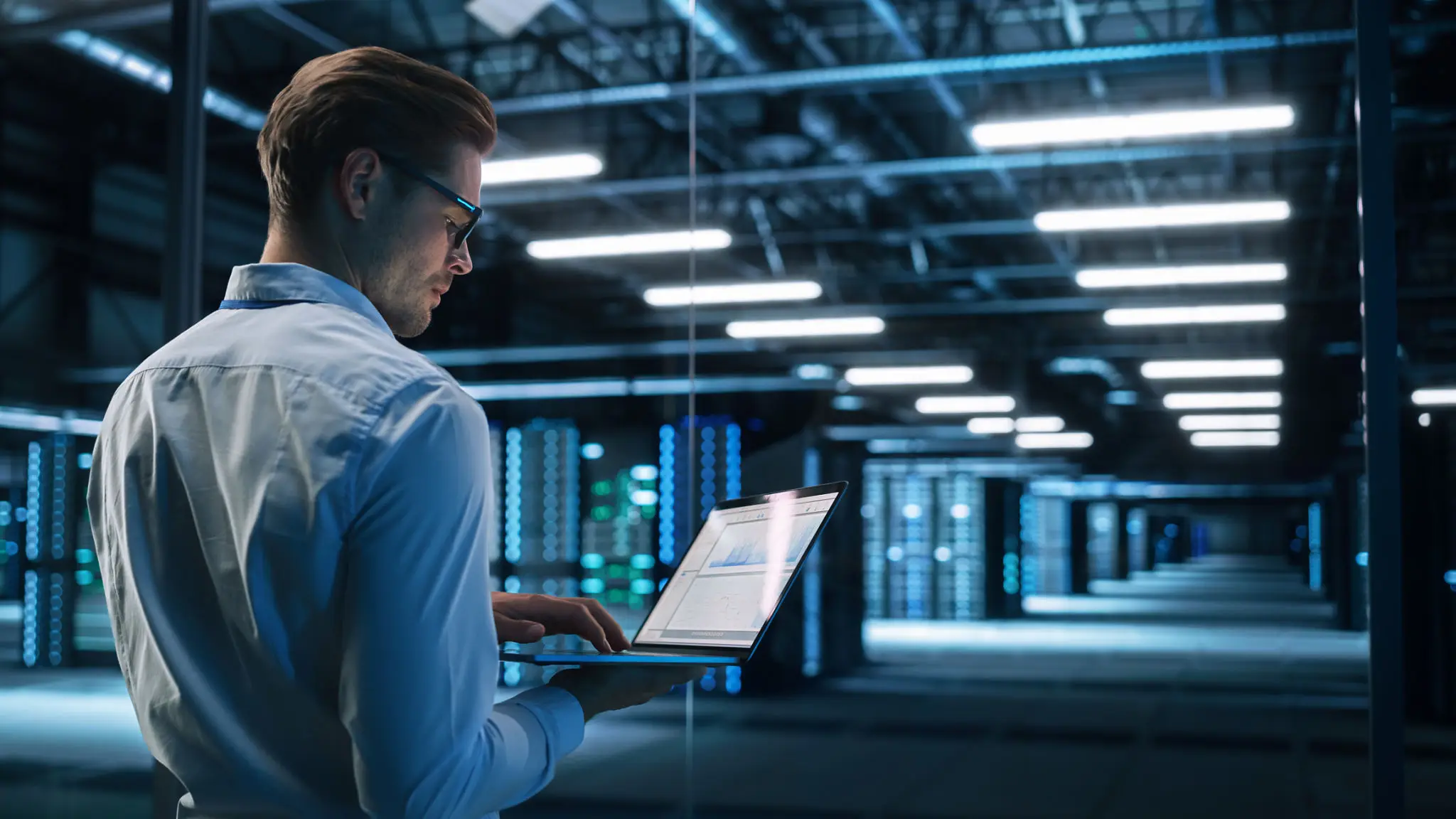 Person using laptop in a server room.
